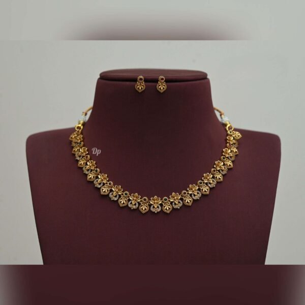 Elegant gold replica necklace set with intricate kundan work, green stones, and pearl embellishments, paired with matching statement earrings, perfect for weddings and festive occasions.