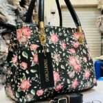 Stylish black handbag adorned with vibrant flower patterns, offering a chic and versatile look for both casual and formal occasions.